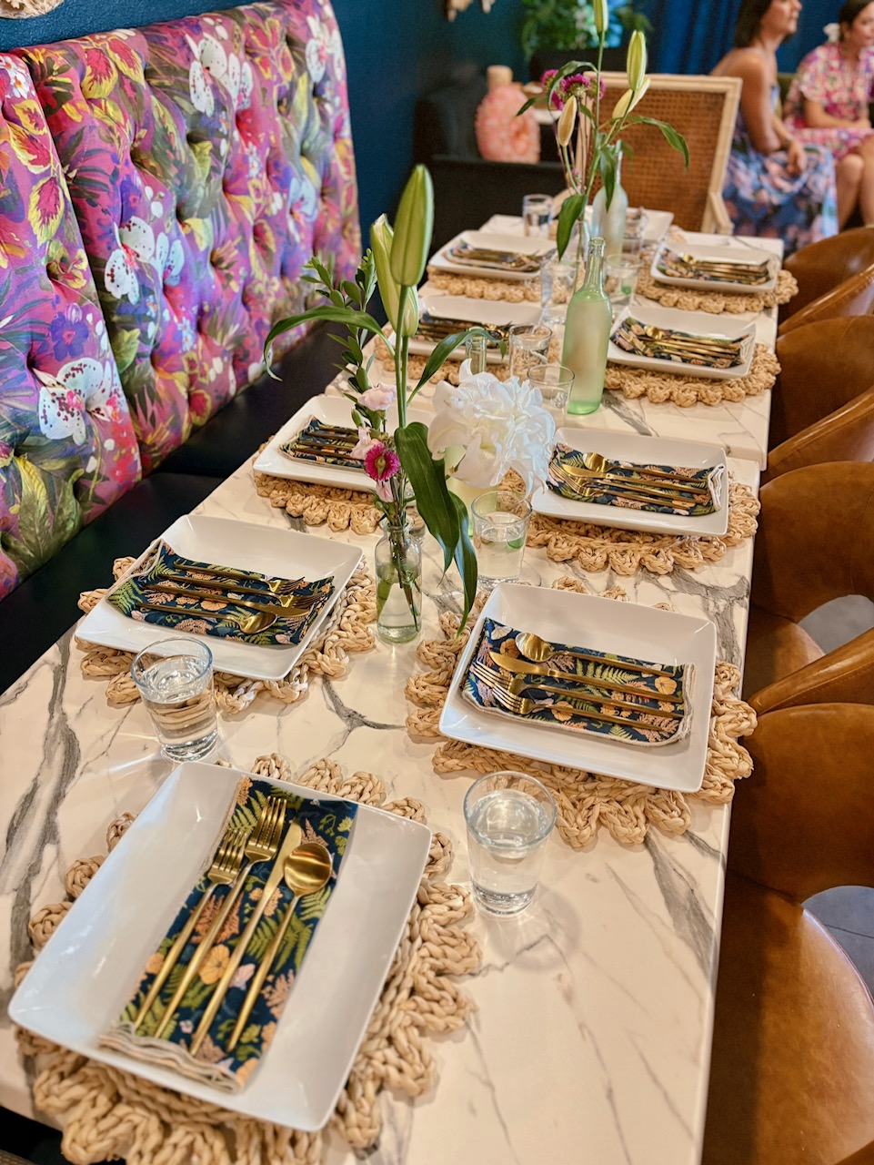 A long table set with gold flatware and floral centerpieces